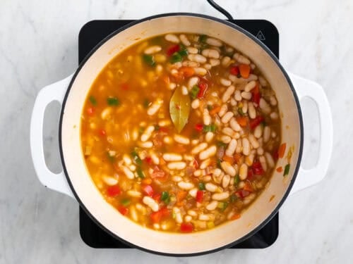 Ingredientes para hacer alubias blancas con verduras en una olla.