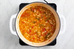 Guiso de alubias blancas con verduras en una olla.