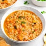 Platos de arroz caldoso con verduras servidos con pan y perejil.