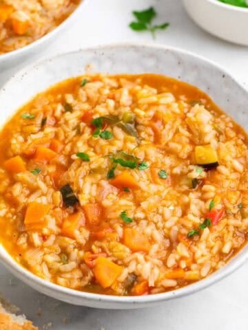 Platos de arroz caldoso con verduras servidos con pan y perejil.
