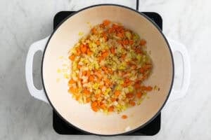 Ajo, cebolla, puerro y zanahoria salteados en una olla.