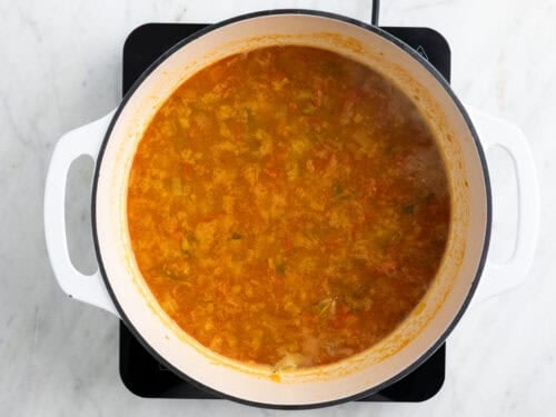 Sofrito, arroz y caldo en una olla.