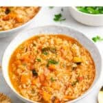 Platos de arroz caldoso con verduras con pan, perejil y un tenedor al lado.