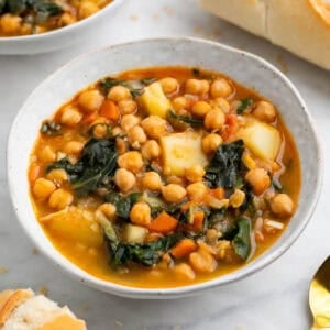 Potaje de garbanzos con acelgas en boles acompañado de pan y cuchara.