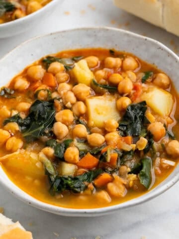 Potaje de garbanzos con acelgas en boles acompañado de pan y cuchara.