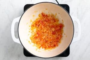 Cebolla, ajo y tomate salteados en una olla.