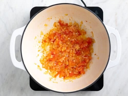 Cebolla, ajo y tomate salteados en una olla.