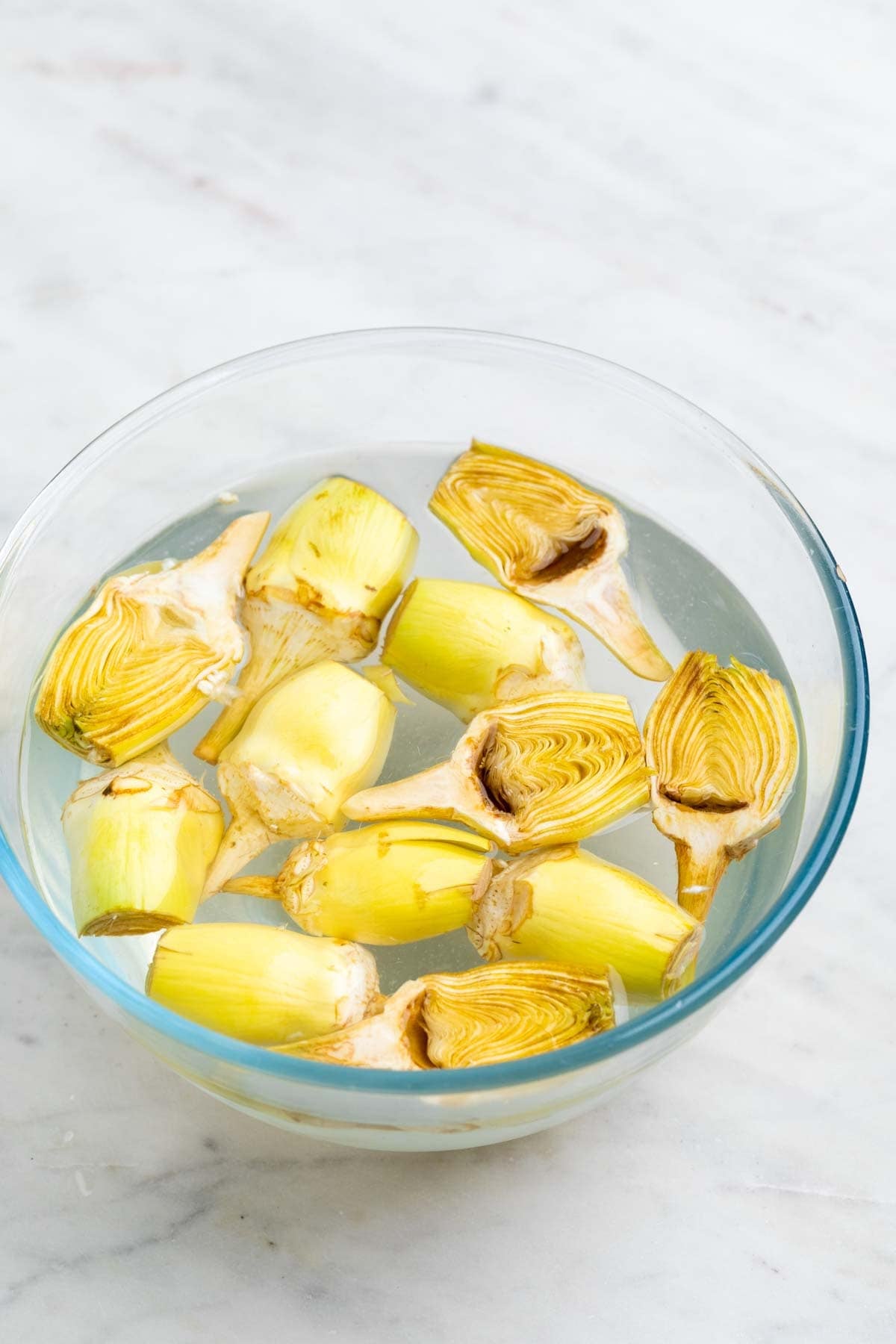 Bol con agua con zumo de limón y alcachofas limpias.