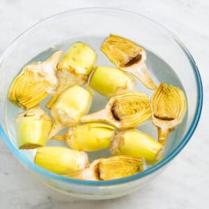 Alcachofas troceadas y limpias en un recipiente con agua y zumo de limón.