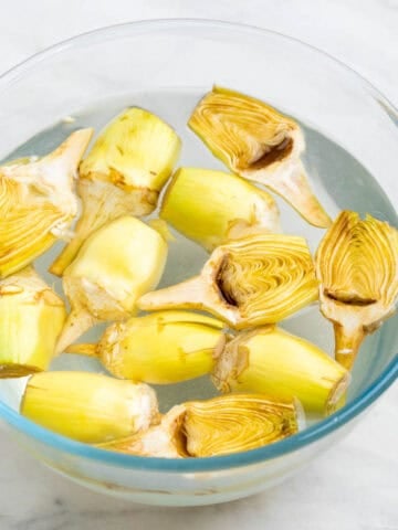 Alcachofas troceadas y limpias en un recipiente con agua y zumo de limón.