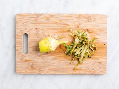 Alcachofa limpia por fuera sobre una tabla.