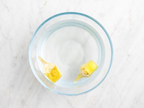 Alcachofa limpia y troceada en un bol con agua y zumo de limón.