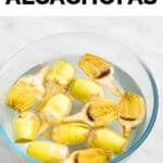 Alcachofas troceadas en mitades y limpias en un bol con zumo de limón y agua.