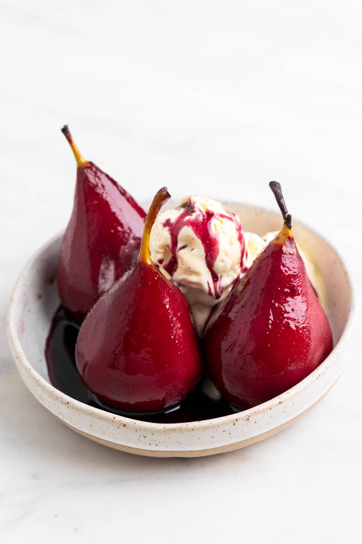 Helado y peras al vino en un plato con alm&iacute;bar.