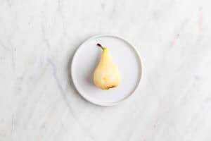 Pera pelada en un plato.