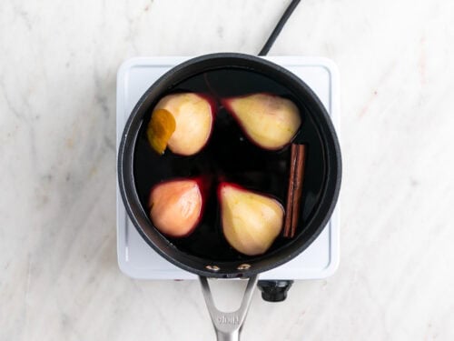 Peras en un cazo con el vino, el azúcar, la canela y la piel de limón.