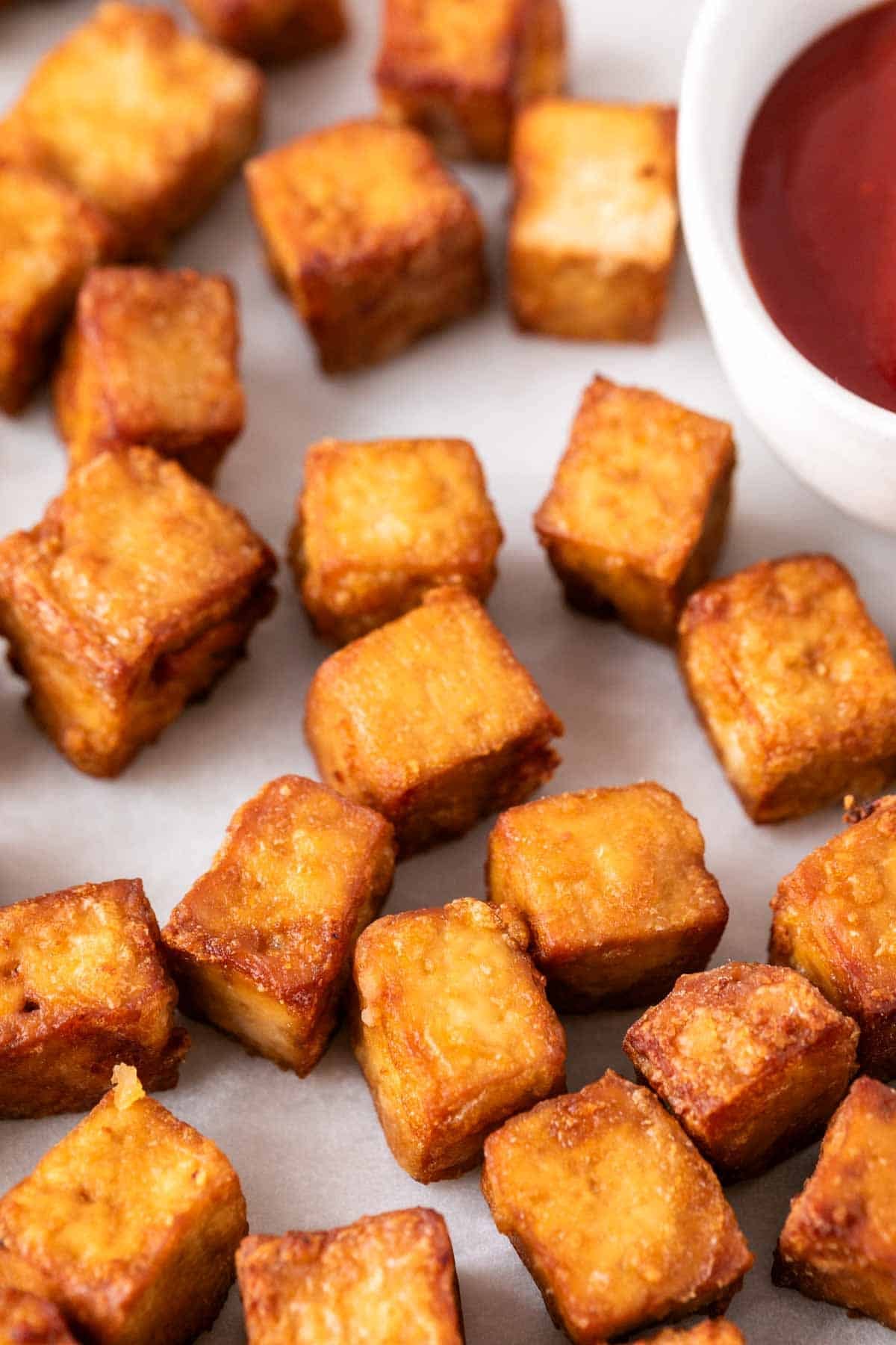 Tofu cocinado en freidora de aire con ketchup al lado.
