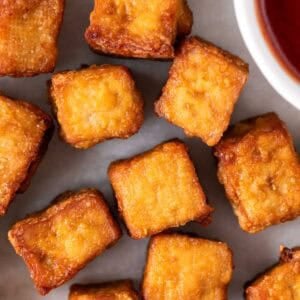 Dados de tofu cocinados en freidora de aire con un cuenco de ketchup.