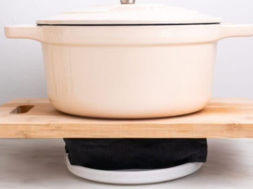 Tofu prensándose envuelvo en un paño de cocina con una olla encima.