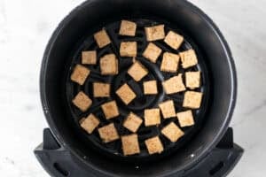 Tofu en la cesta de la freidora de aire antes de cocinarse.