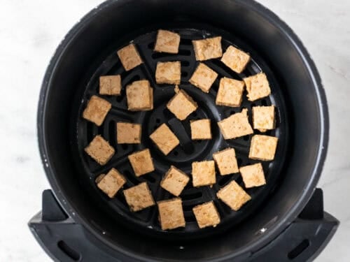 Tofu en la cesta de la freidora de aire antes de cocinarse.