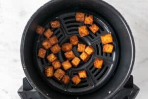 Tofu cocinado en la cesta de la freidora de aire.