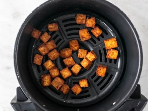 Tofu cocinado en la cesta de la freidora de aire.