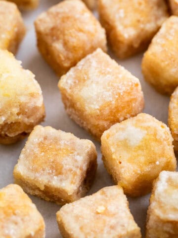 Tofu frito en dados dorados sobre papel de horno.