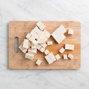 Tofu en dados en una tabla de cortar.