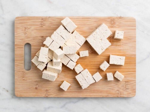 Tofu en dados en una tabla de cortar.