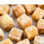 Dados de tofu frito sobre papel de horno.