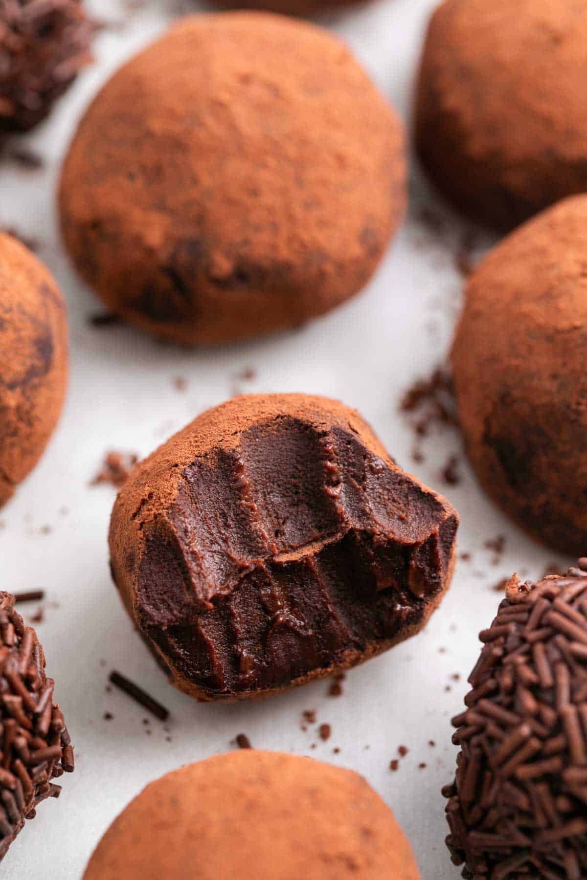 Trufas de chocolate, unas con cacao y otras con fideos de chocolate, con una trufa mordida.