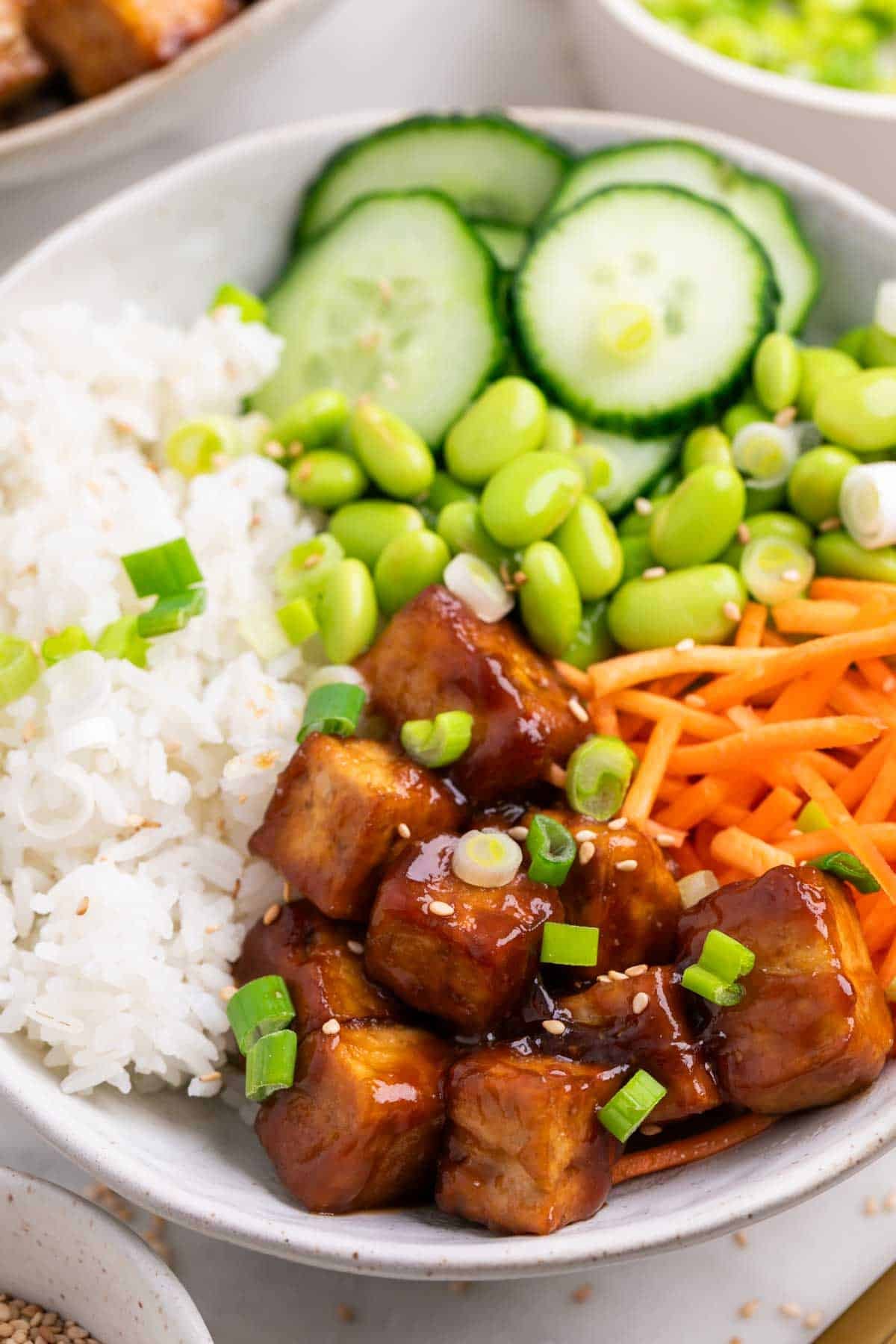 Boles de arroz con tofu crujiente y verduras, decorados con sésamo y cebolleta