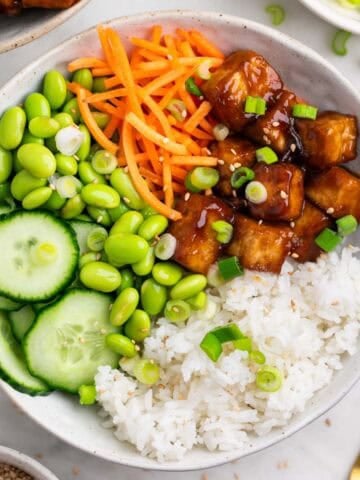 Arroz con tofu crujiente servido en boles, con semillas de sésamo y cebolleta