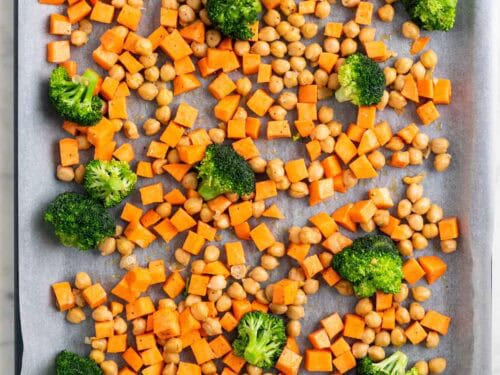 Garbanzos, br&oacute;coli y boniato en una bandeja para horno antes de hornear
