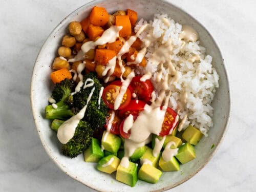 Bol con arroz, verduras asadas, verduras crudas y ali&ntilde;o de tahini por encima