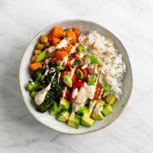 Bol de arroz con verduras y aliño de tahini decorado con sésamo y cebolleta