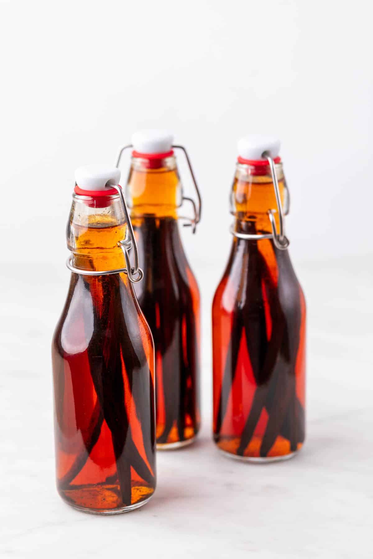 Botellas con extracto de vainilla casero oscuro y vainas de vainilla tras 3 meses