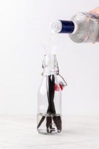 Echando vodka en una botella con vainas de vainilla dentro