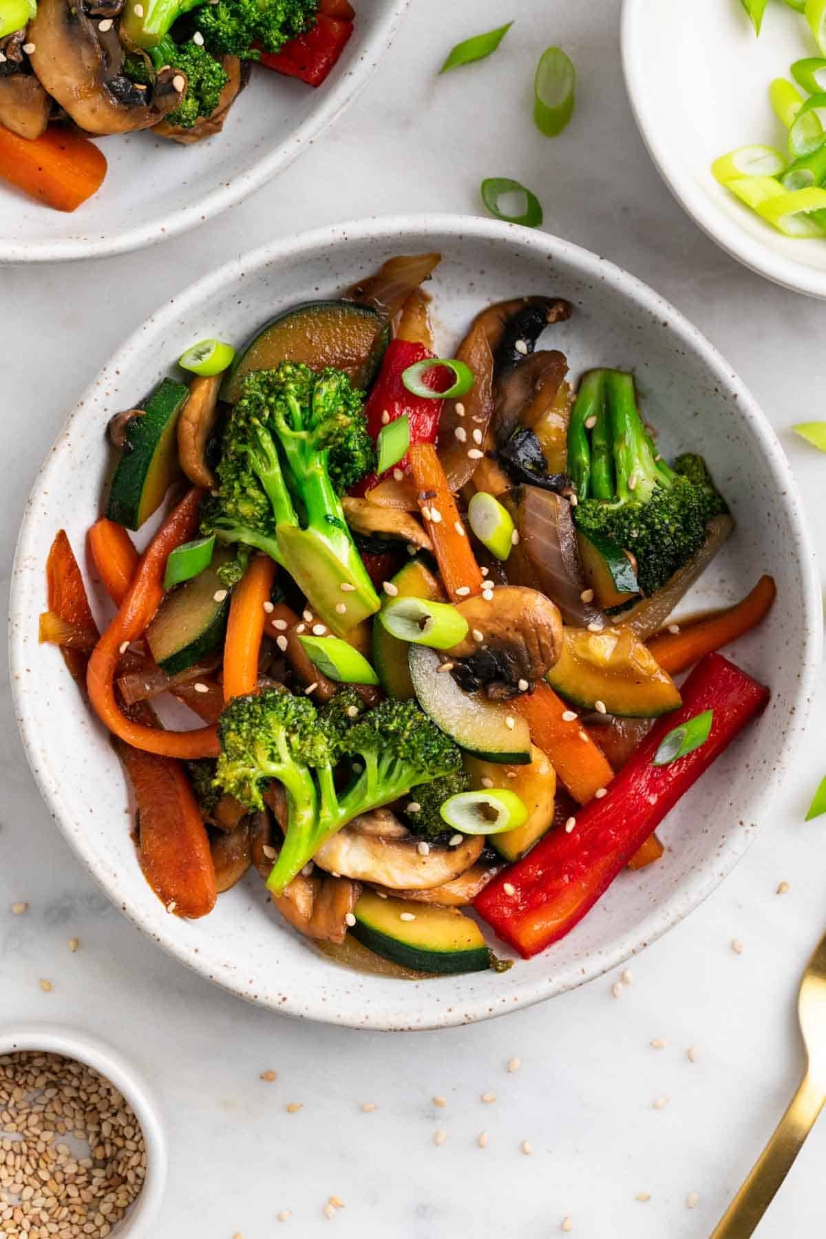 Salteado de verduras en dos platos con cebolleta y s&eacute;samo.