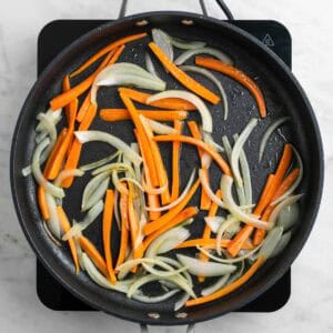 Cebolla y zanahoria salteadas en una sartén.