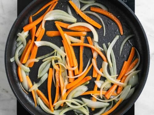 Cebolla y zanahoria salteadas en una sartén.