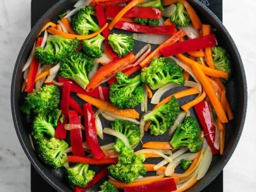 Cebolla, zanahoria, pimiento y brócoli salteados en una sartén.