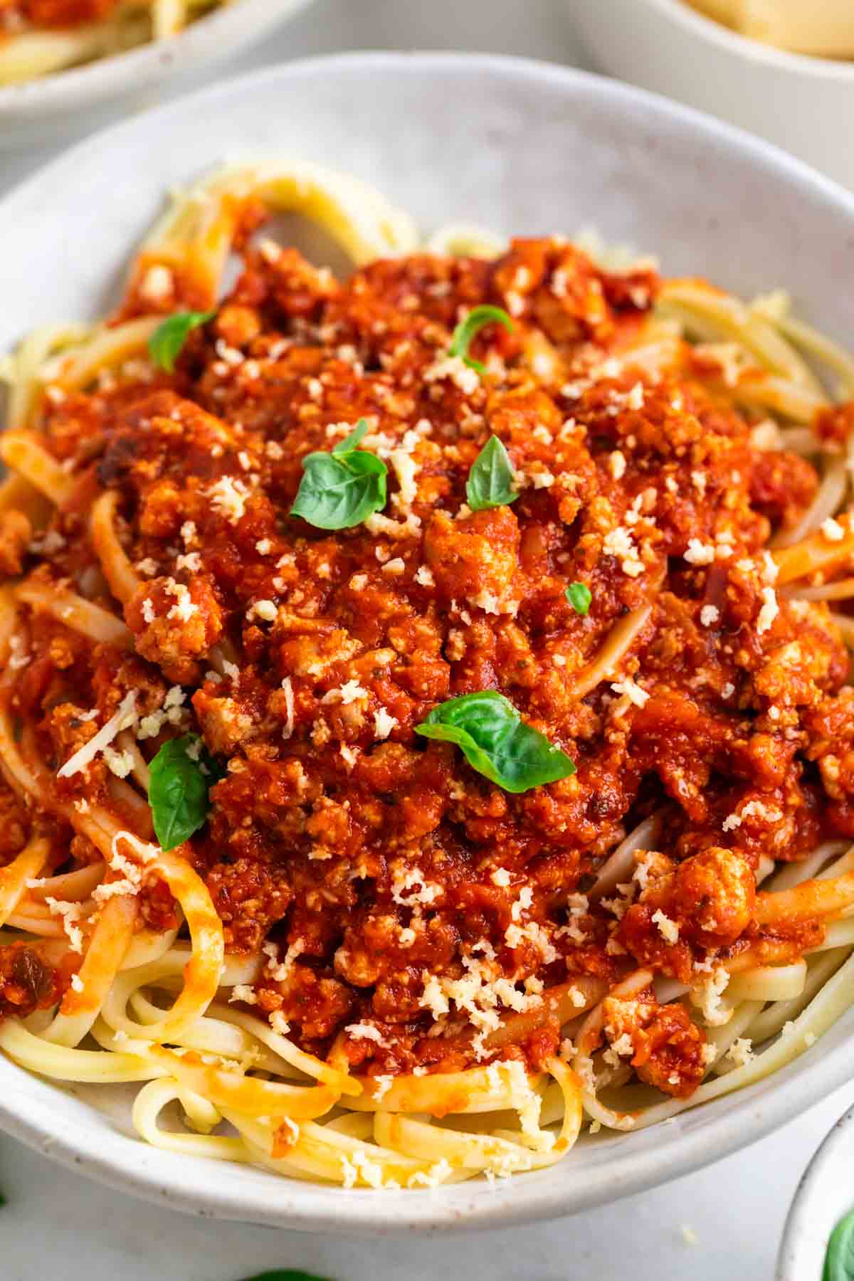 Espaguetis con salsa boloñesa de tofu servidos con albahaca y parmesano vegano