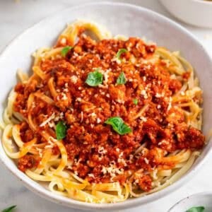 Plato de pasta con boloñesa de tofu y queso parmesano vegano por encima