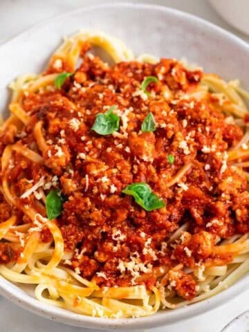 Plato de pasta con boloñesa de tofu y queso parmesano vegano por encima