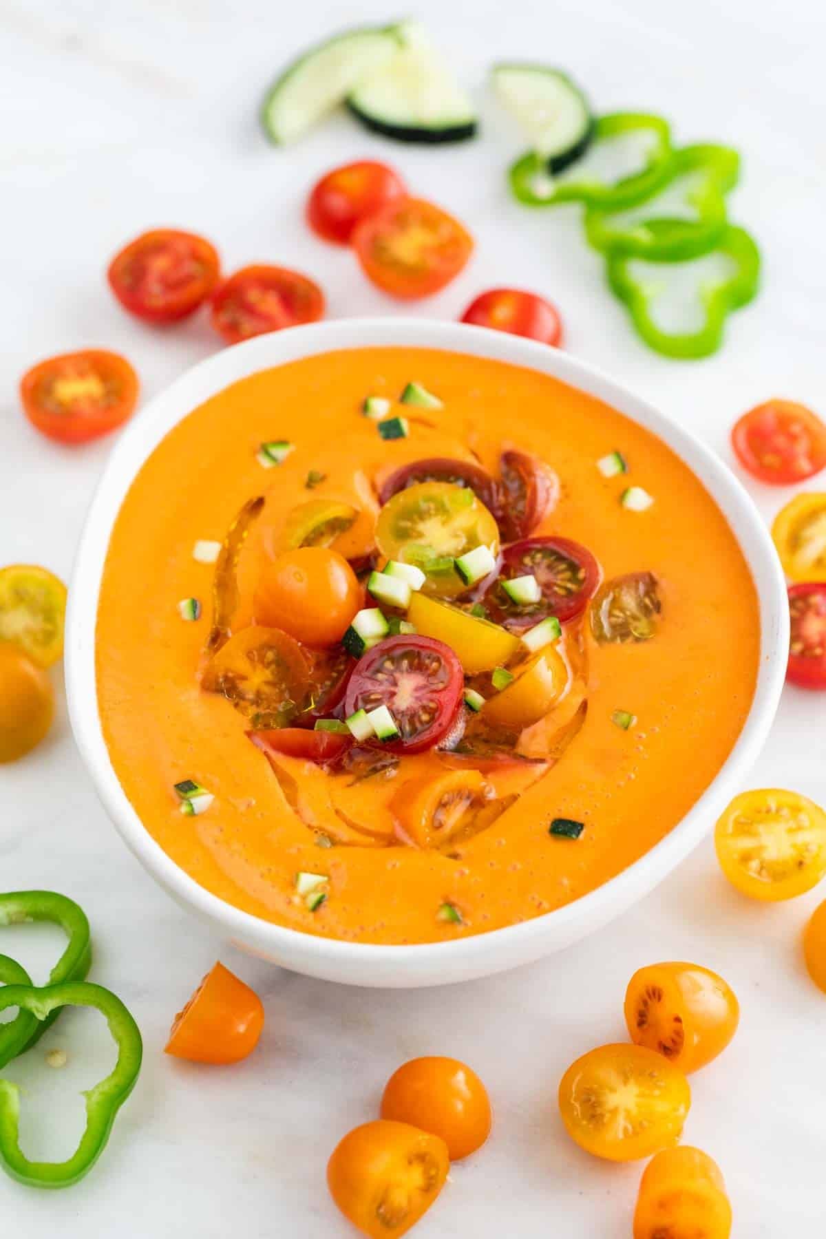 Bol de gazpacho andaluz decorado con aceite de oliva, tomates cherry y pepino troceado