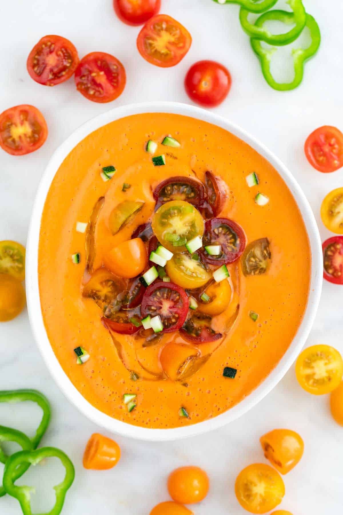 Gazpacho andaluz servido en un bol con aceite de oliva, tomates cherry y pepino troceado