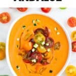 Gazpacho andaluz en un bol decorado con aceite de oliva, tomates cherry y pepino troceado