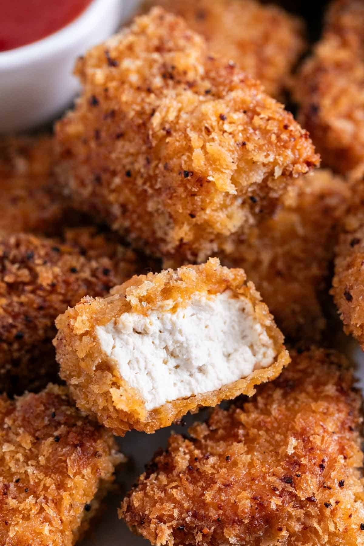 Nuggets veganos de tofu con ketchup y un nugget mordido